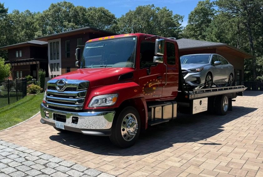 Centri Auto flatbed truck delivering a sedan in a Rhode Island driveway