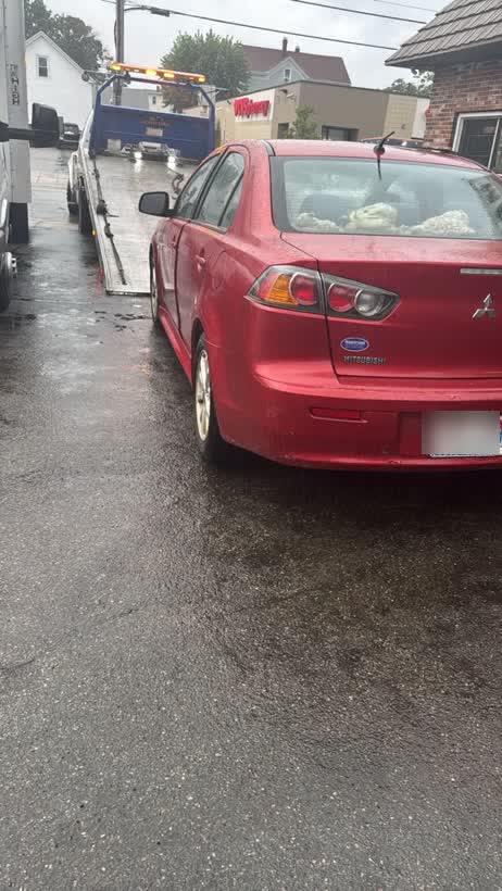 Red sedan being winched onto the flatbed