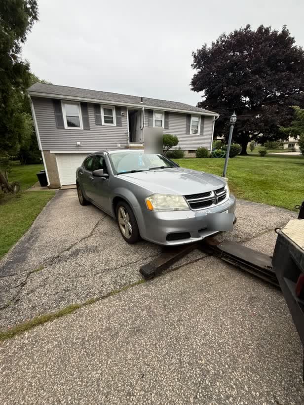 Silver sedan being winched from a driveway